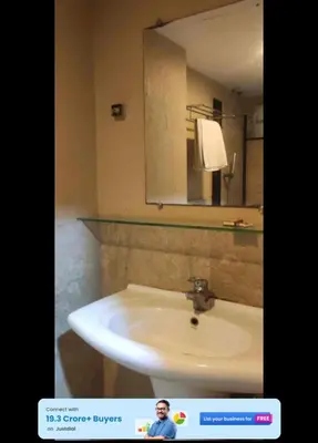 a man standing in front of a bathroom sink at Mysore Central 3bhk serviced apartment in Mysore