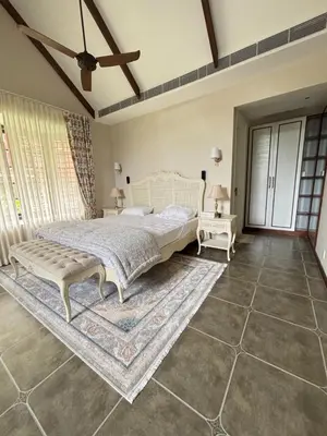 a bedroom with a bed and a rug at Hanberry Luxury Cottage in Kalpetta