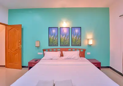 a bedroom with a bed with three paintings on the wall at Pine Forest View Ooty by VOYE HOMES in Ooty