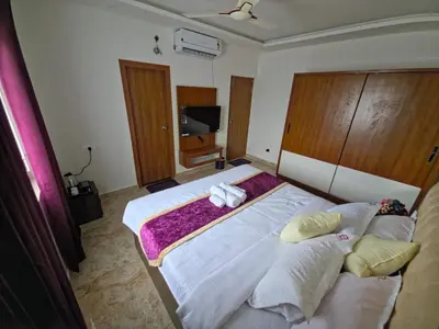 a bedroom with a large bed with three pillows at Broadway Inn in Mysore