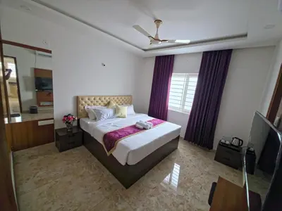 a bedroom with a large bed with purple curtains at Broadway Inn in Mysore