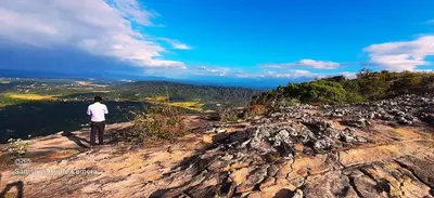 a man standing on top of a rocky mountain at Naturia in Ambalavayal