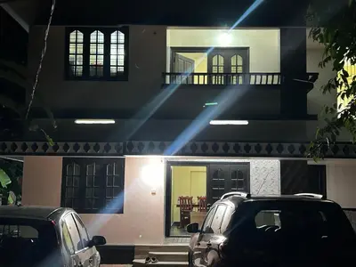 two cars parked in front of a house at night at Bluebell Homes B- 2bhk Upstairs in Kozhikode