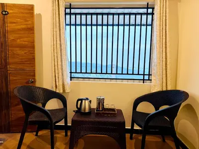 two chairs and a table in front of a window at Humming Bird By Brown Tree Resorts in Kotagiri