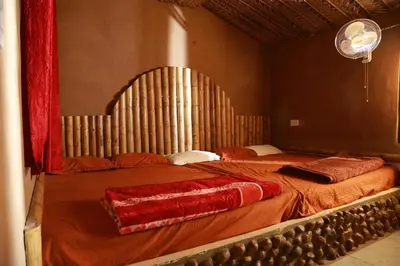 a bedroom with a large bed with red sheets at Vihara Mudcamp in Marayoor