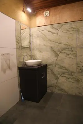 a bathroom with a sink and a marble wall at Vihara Mudcamp in Marayoor