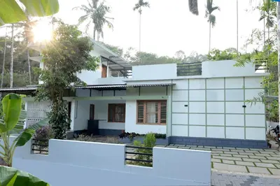 a white house with palm trees in the background at Malayil Peacock Villa in Wayanad