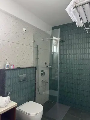 a bathroom with a toilet and a glass shower at Event House, Mysore in Mysore
