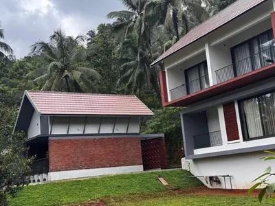 a house with a red roof and two palm trees at GINGY Holidays in Wayanad
