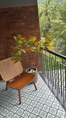 a bench and a potted plant on a balcony at GINGY Holidays in Wayanad