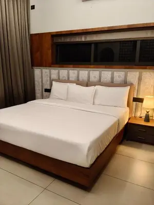 a bedroom with a large bed with white sheets at GINGY Holidays in Wayanad