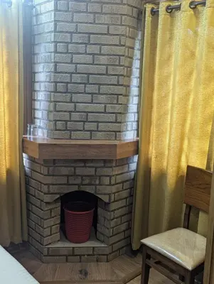 a brick fireplace in a room with a chair at Ivy hostel ooty in Ooty