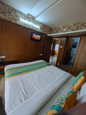 a large white bed in a room with a tv at Ivy hostel ooty in Ooty