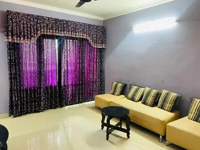 a living room with two yellow couches and purple curtains at 2BHK Apartment in Central Thrissur in Trichūr