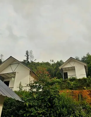 two white buildings sitting on top of a hill at Tribano vattavada in Vattavada