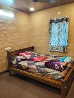 a bedroom with a wooden bed with a window at BREEZE GARDEN MUD HOUSE Home Stay in Kanthalloor