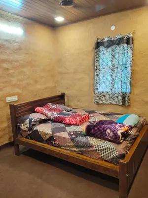 a bedroom with a wooden bed with a window at BREEZE GARDEN MUD HOUSE Home Stay in Kanthalloor