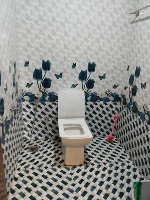 a bathroom with a toilet with blue flowers on the wall at BREEZE GARDEN MUD HOUSE Home Stay in Kanthalloor