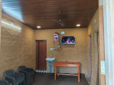 a room with a table and a sink and a tv at BREEZE GARDEN MUD HOUSE Home Stay in Kanthalloor