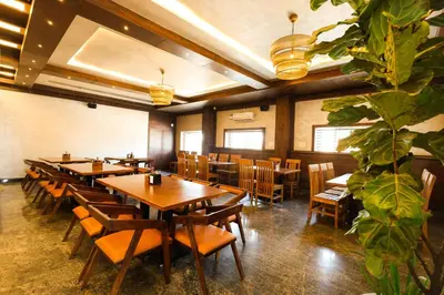 a restaurant with wooden tables and chairs and a plant at SSR Comforts in Mandya