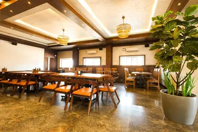 a restaurant with wooden tables and chairs and a potted plant at SSR Comforts in Mandya