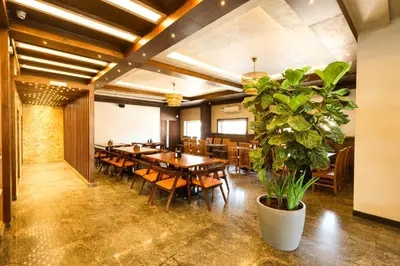 a restaurant with wooden tables and chairs and a potted plant at SSR Comforts in Mandya
