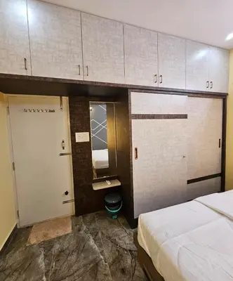 a room with a bed and a bathroom with cabinets at Suhas Nest in Mysore