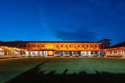 a large building with a green lawn in front of it at Kamath Village Resortz
