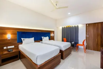 a bedroom with two beds and a desk and a tv at Kamath Village Resortz