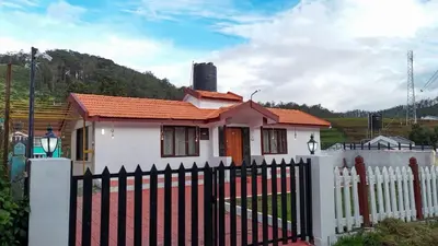 a small house with a white fence and a white picket fenceasteryasteryastery at Hertz home in Ooty