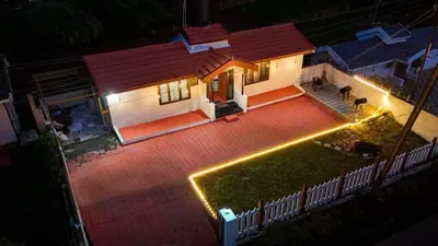 a house with lights in front of a yard at Hertz home in Ooty
