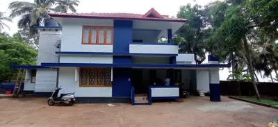 a blue and white house with a scooter parked in front at Perch by the sea 2 in Kannur