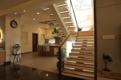 a staircase in a living room with a kitchen at Mon Reve - Home in the valley in Puthuppādi