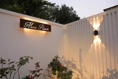 a sign on the side of a white fence at Mon Reve - Home in the valley in Puthuppādi