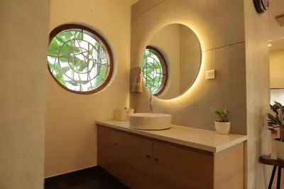a bathroom with a sink and a round mirror at Mon Reve in Kozhikode
