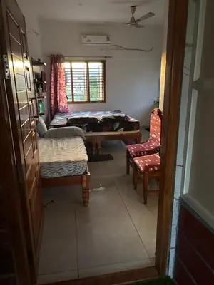 a room with a bed and a chair and a window at Private Room with Kitchen for Decent Couples & Families in Mysore