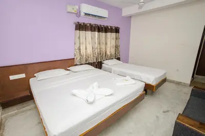 two beds in a room with white sheets at Parva Residency in Palladam