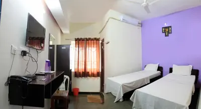 a hospital room with two beds and a tv at Parva Residency in Palladam