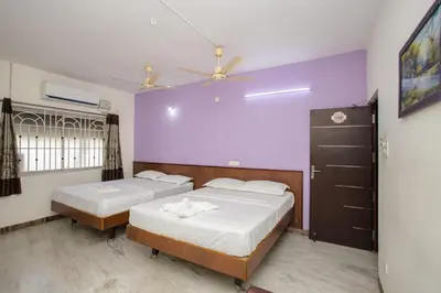 a bedroom with two beds and a ceiling fan at Parva Residency in Palladam