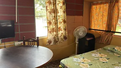 a room with a table and a fan and a window at Garden Room for a Couple in Mysore