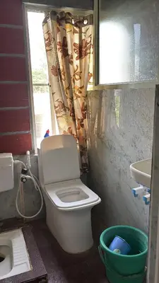 a bathroom with a toilet and a sink and a window at Garden Room for a Couple in Mysore