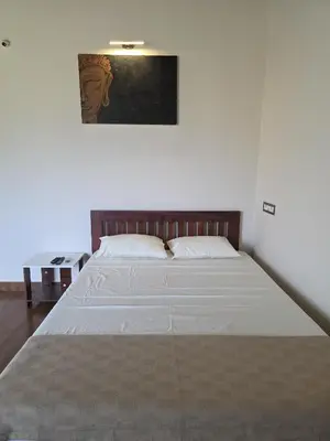 a bedroom with a large bed with white sheets at Rangers Nest Bandipur in Gundlupet
