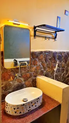 a bathroom with a sink and a tv on a wall at Rangers Nest Bandipur in Gundlupet