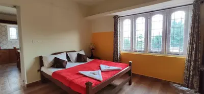 a bedroom with a bed with red sheets and a window at Nivriti Cottage Valley View Stay in Ooty
