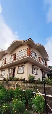 a large house with a balcony on top of it at Nivriti Cottage Valley View Stay in Ooty