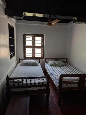 two beds in a room with a window at Traditional Kerala house, Thalassery, Kannur in Tellicherry
