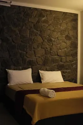 a bedroom with a stone wall with a bed at Skyfall adventure rooms in Meppādi