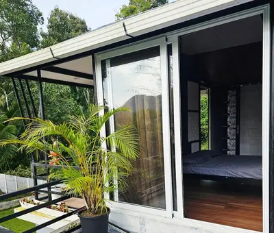 a screened in porch with a bed and a plant at Valiyattu Nest Homestay in Ambalavayal