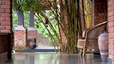 a brick wall with a bench and a plant at Clayfingers Art Cottage in Trichūr