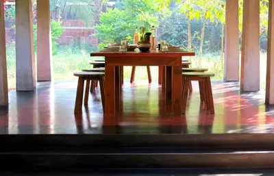 a wooden table with two chairs in a room at Clayfingers Art Cottage in Trichūr